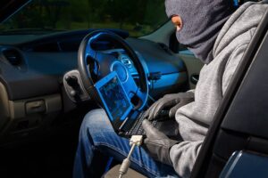 Car thief stealing a car. Starting the car with a lap top
